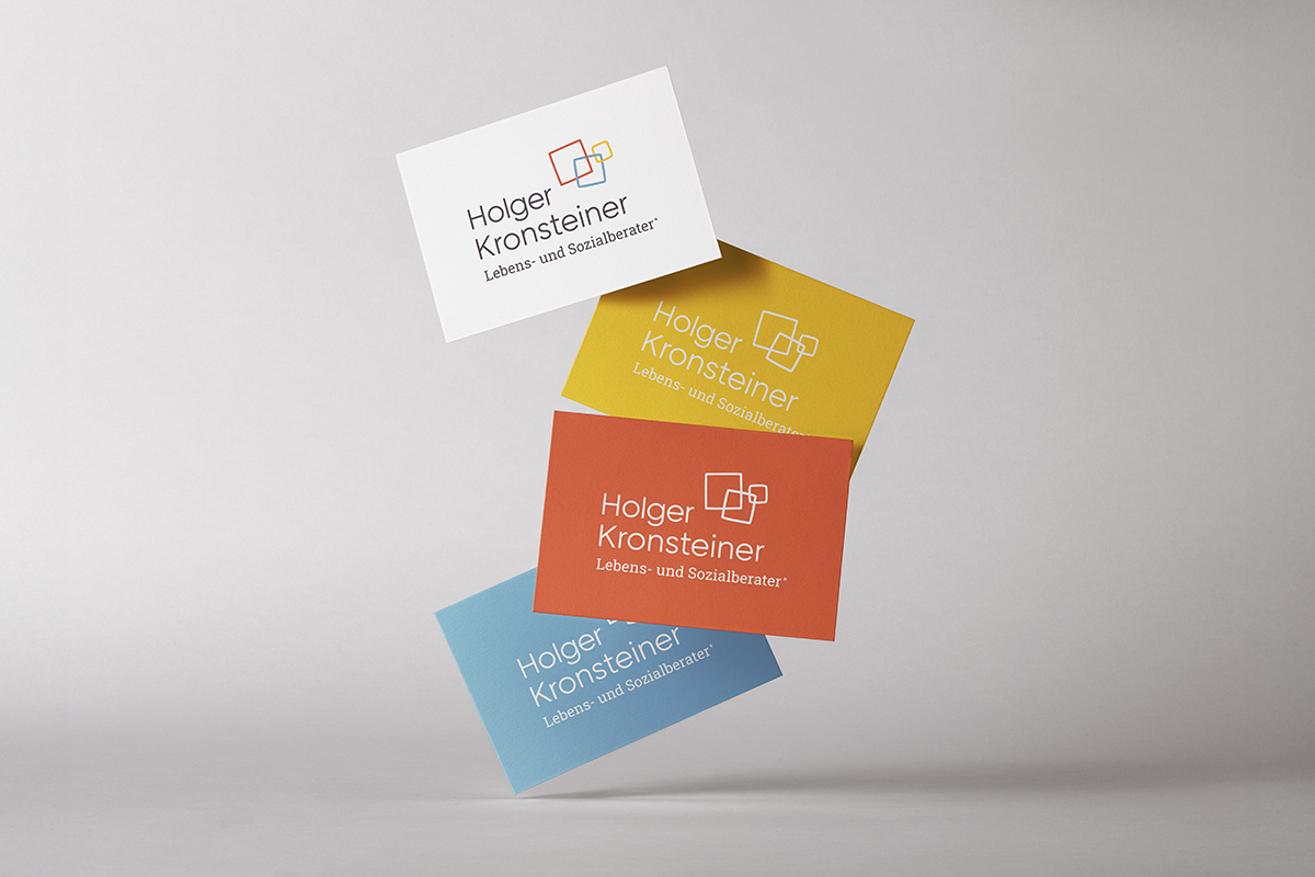 Foto mit vier Farbvarianten der Visitenkarten für Holger Kronsteiner, Lebens- und Sozialberater in Ausbildung und unter Supervision. Das Foto zeigt die Vorderseite der Visitenkarten in vier Farbvarianten in einer fallenden Bewegung. Oben ist die Variante in Weiß mit färbigem Logo, darunter die Karten in Gelb, Orange und Blau jeweils mit weißem Logo. Copyright © 2025 Olivia Weise, Design & Illustration
